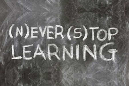 Frase en inglés “never stop learning” escrita con tiza blanca sobre una pizarra, inspirando la preparación académica de idiomas.