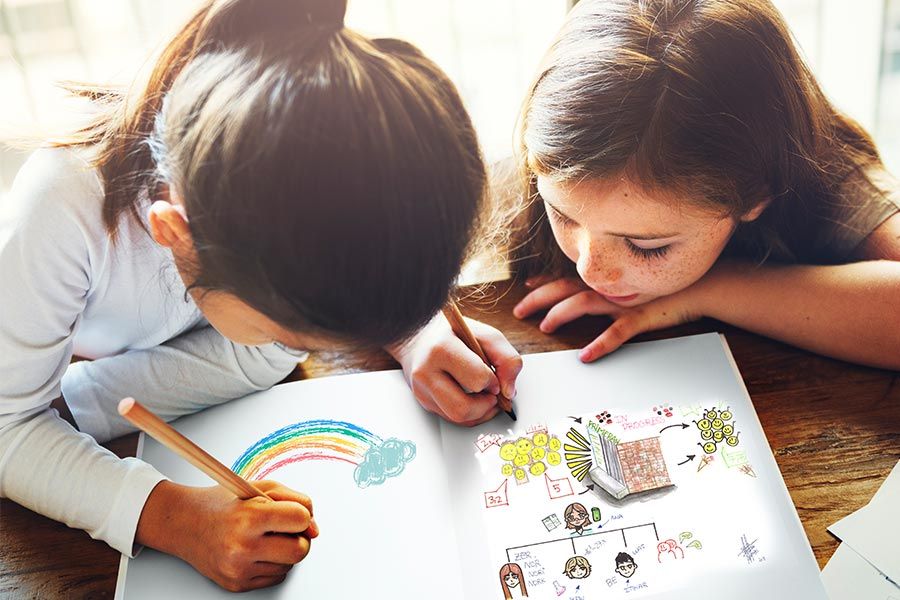 Dos niñas de primaria dibujando y haciendo ejercicios escolares en un cuaderno como parte de refuerzo escolar.